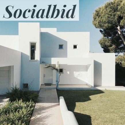 A minimalist modern white house exterior with clean lines and geometric shapes, set against a clear blue sky.